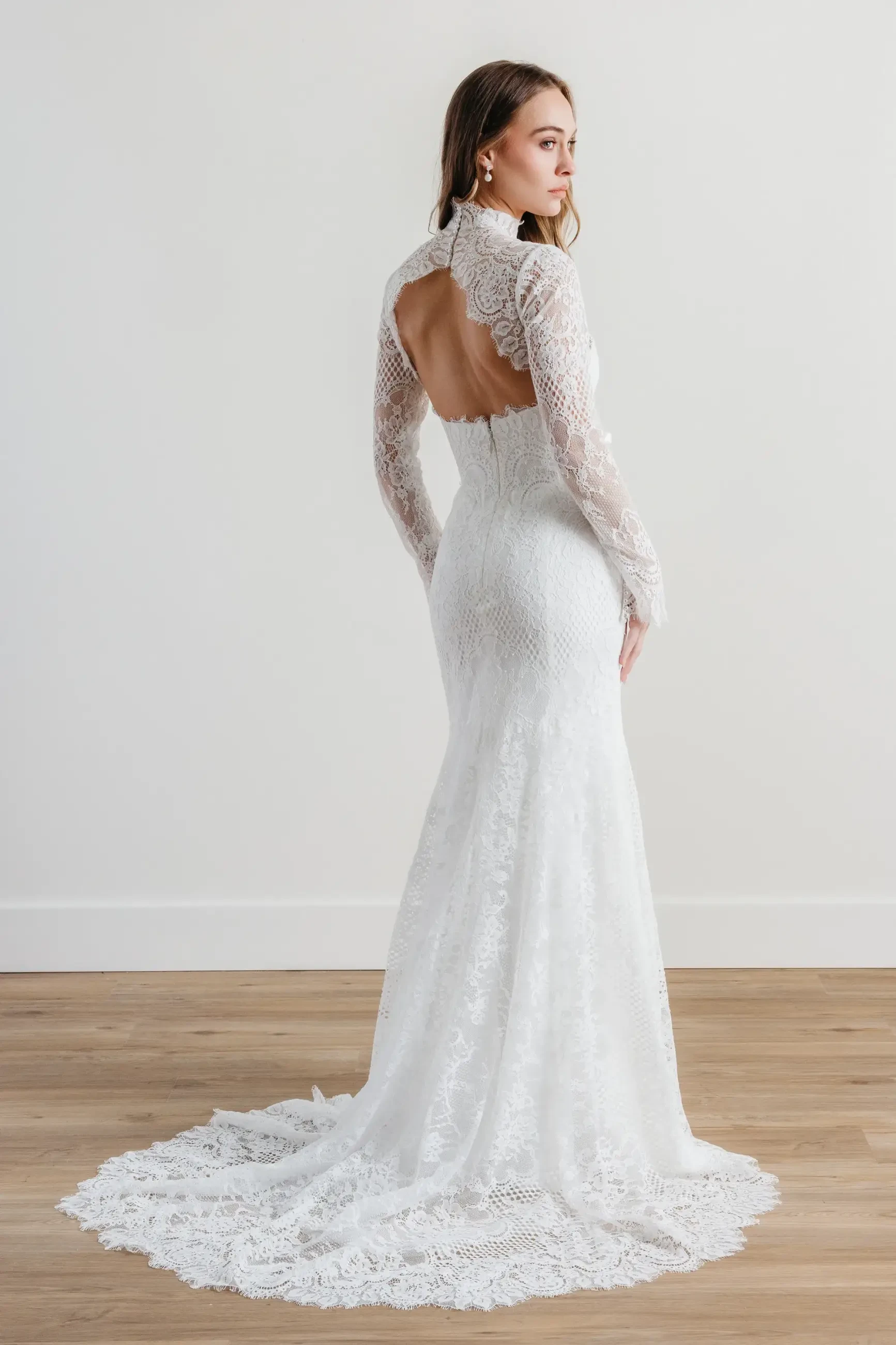 model is wearing an open back wedding dress with a long train 