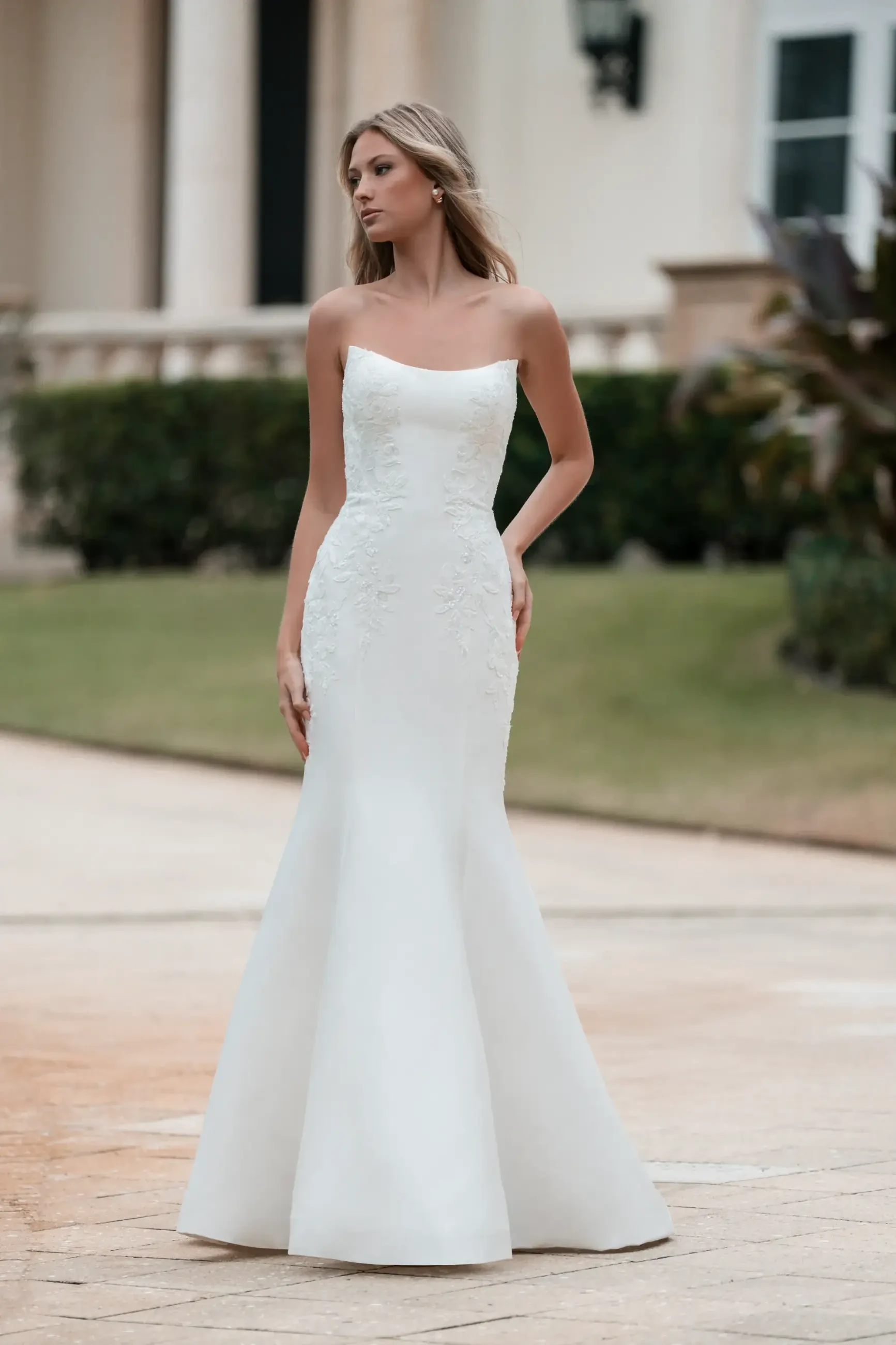 Model is wearing a fit-and-flare Mikado gown with a cat-eye neckline, sequin lace appliques, and detachable lace drop sleeves.