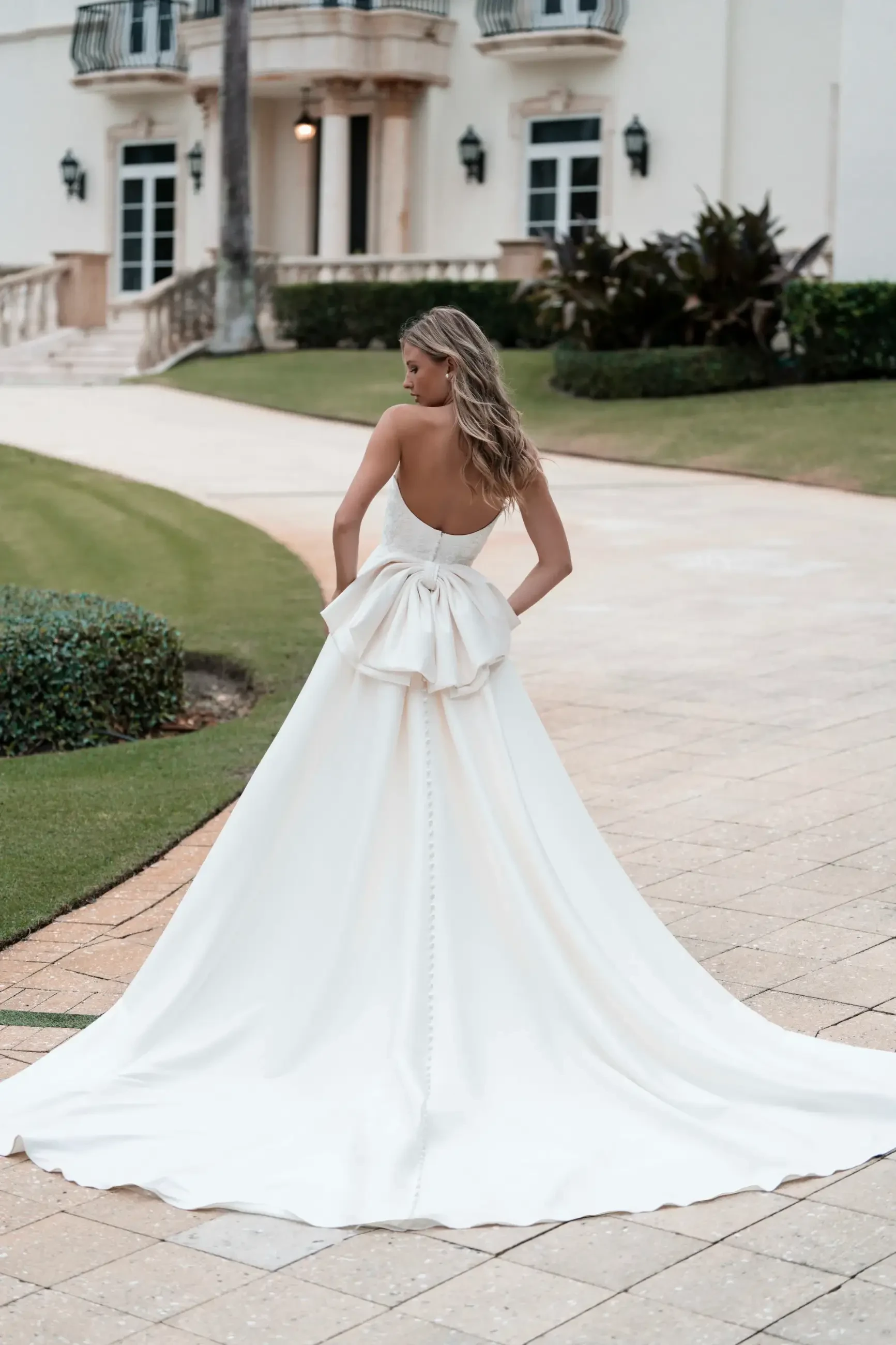 Model is wearing a fit-and-flare Mikado gown with a cat-eye neckline, sequin lace appliques, and detachable lace drop sleeves.
