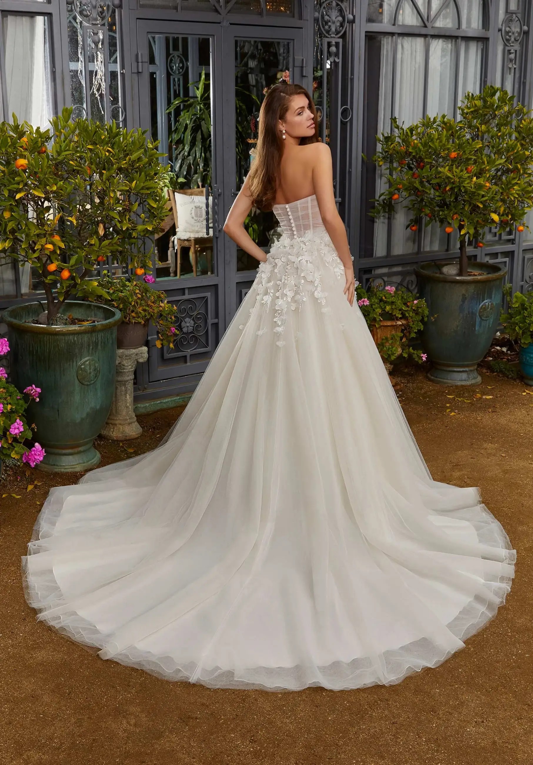 Model is wearing a wedding dress with a corset bodice and full tulle skirt and 3D floral texture