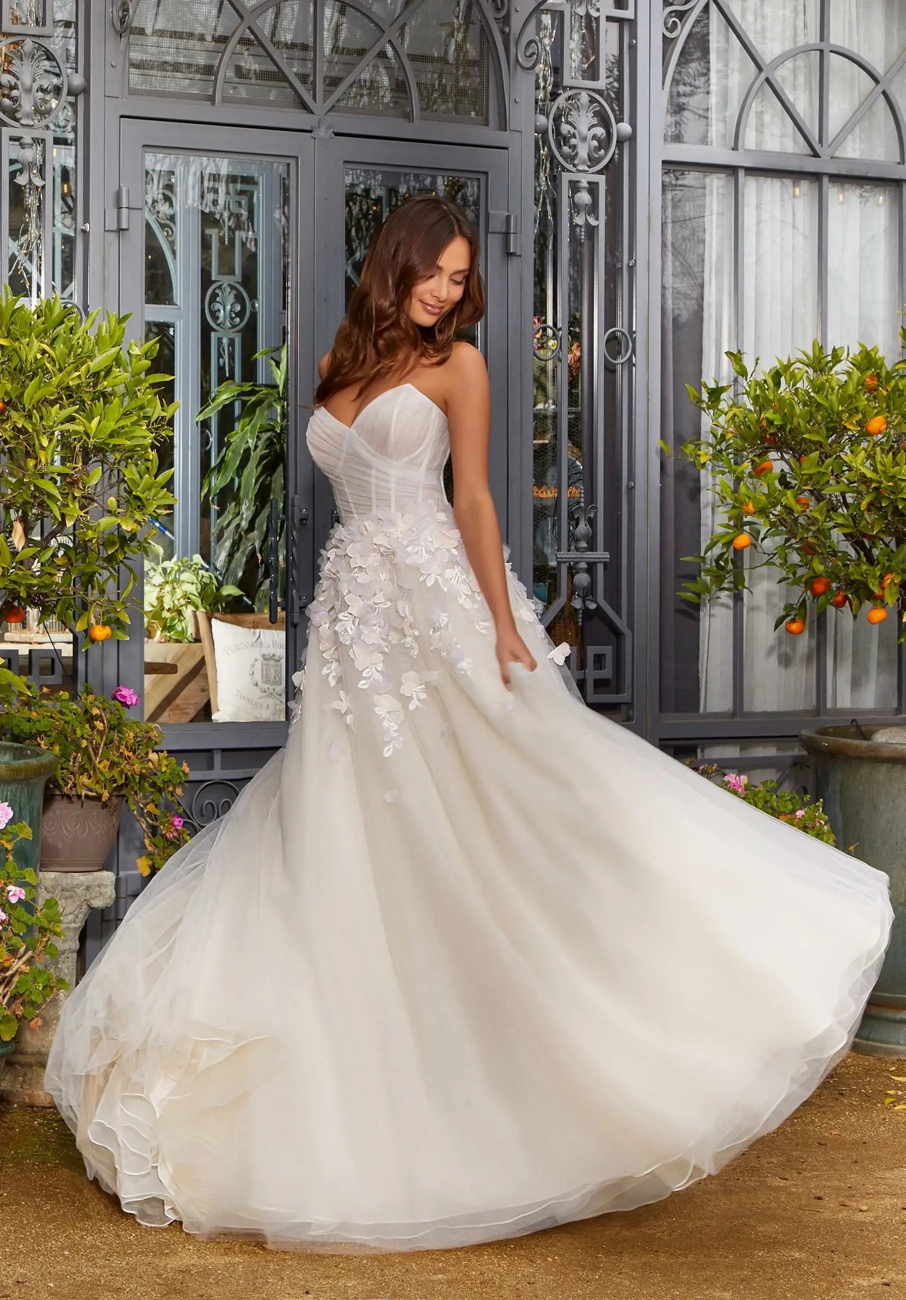 Model is wearing a wedding dress with a corset bodice and full tulle skirt and 3D floral texture