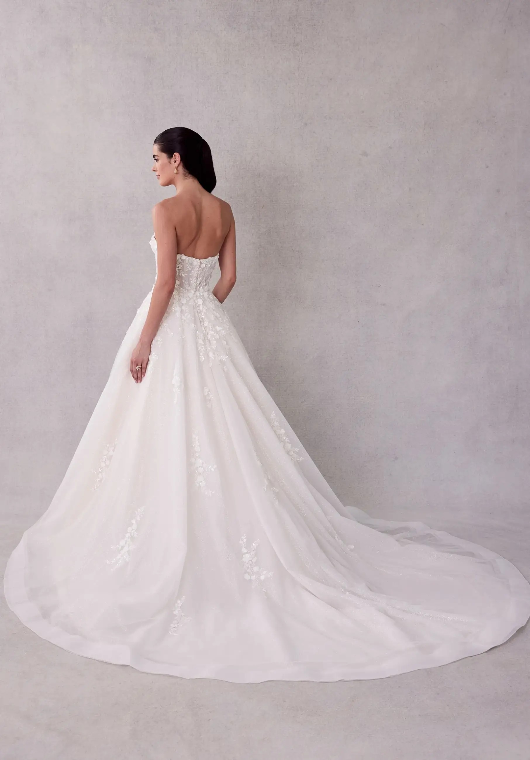 Model is wearing a ball gown wedding dress with a strapless sweetheart neckline with a draped tulle bodice